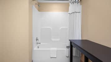 A bathroom with a bathtub, a shower curtain, and a towel hanging on the wall.