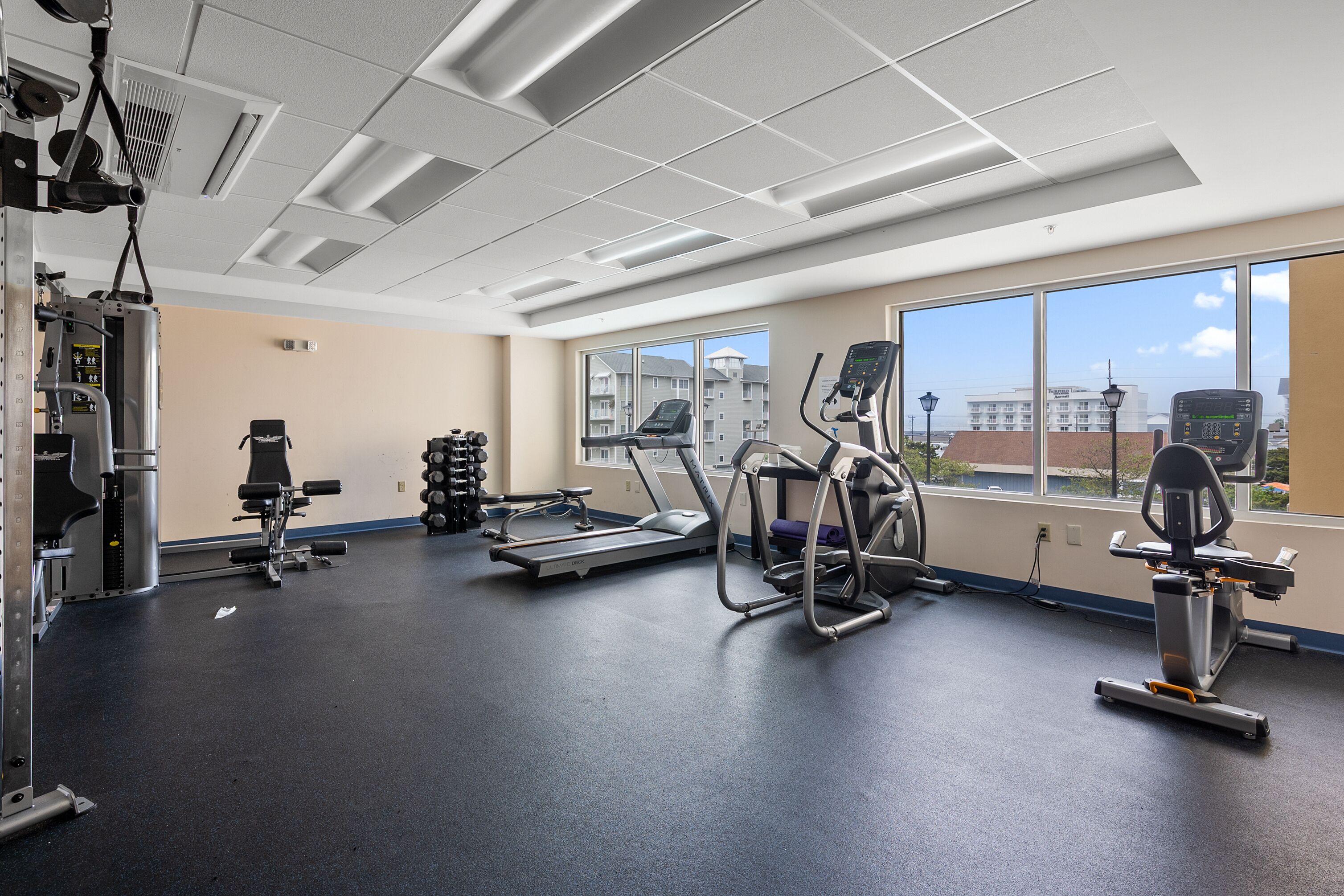 Une salle de sport équipée de tapis de course, de vélos elliptiques et d’appareils de musculation.