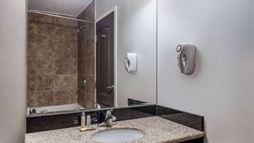 Un bagno moderno con un piano in granito, un lavandino, uno specchio e un dispenser di sapone a portata di mano.