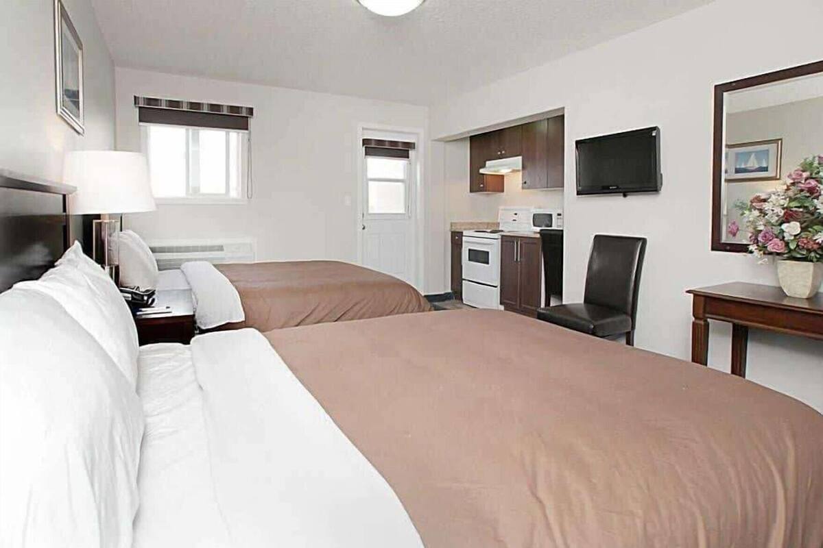 Habitación de hotel con dos camas, un escritorio, una silla, un televisor y un microondas.