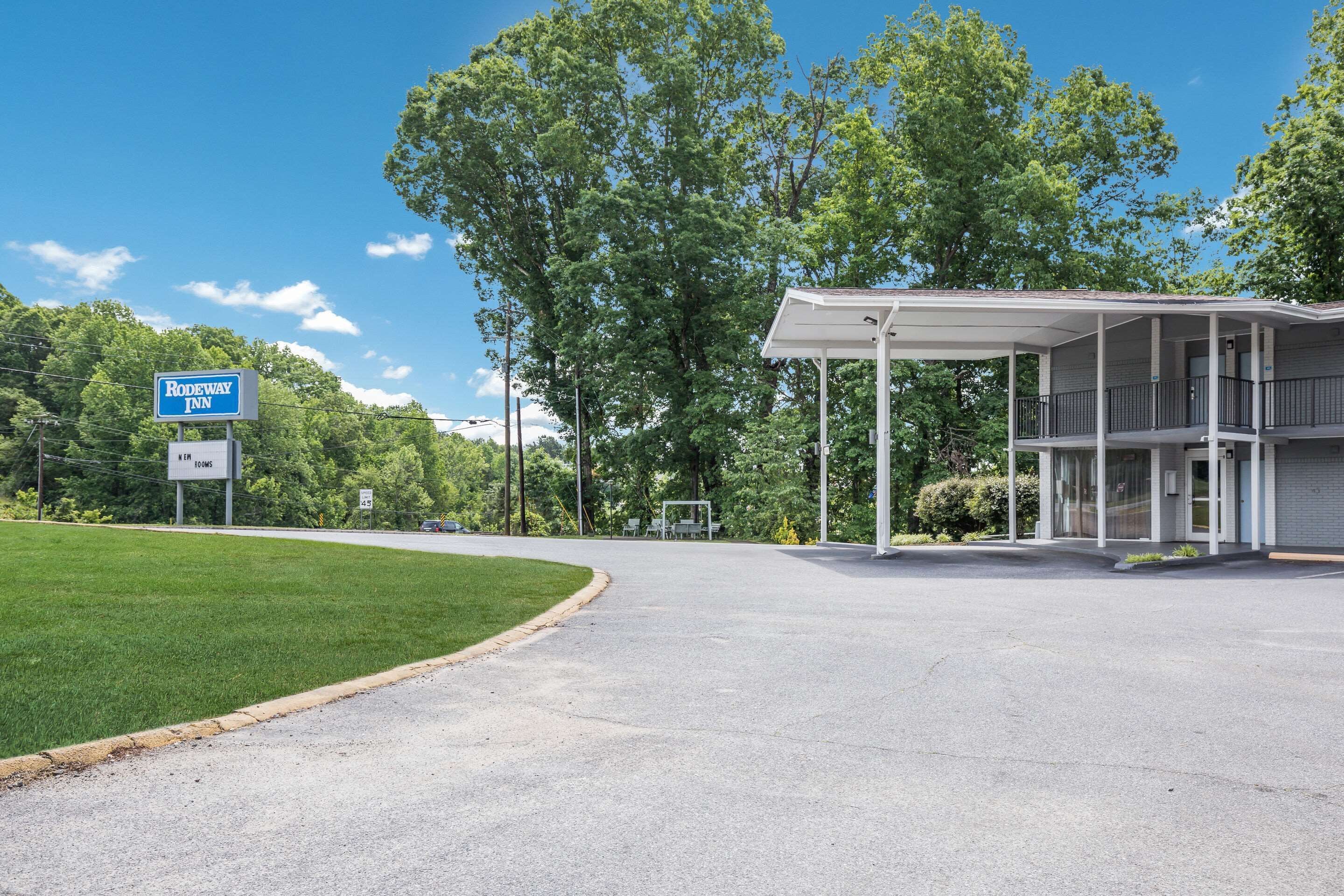 A motel with a covered parking area, a signboard, and a building with a porch.