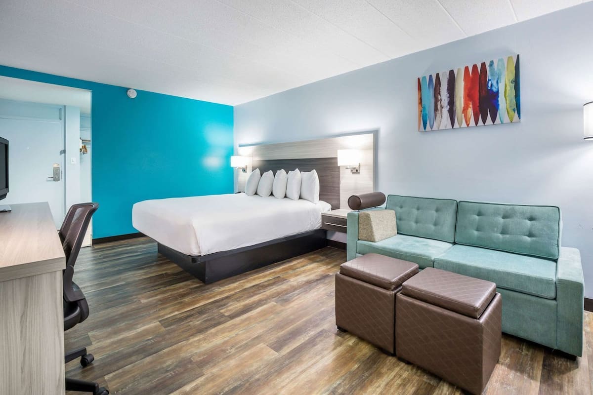 A hotel room with a bed, a sofa, a desk, and a chair.