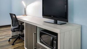 A modern office space with a flat-screen monitor, a desk lamp, a black office chair, and a built-in microwave. - Rodeway Inn Anderson North - Clemson (Anderson)