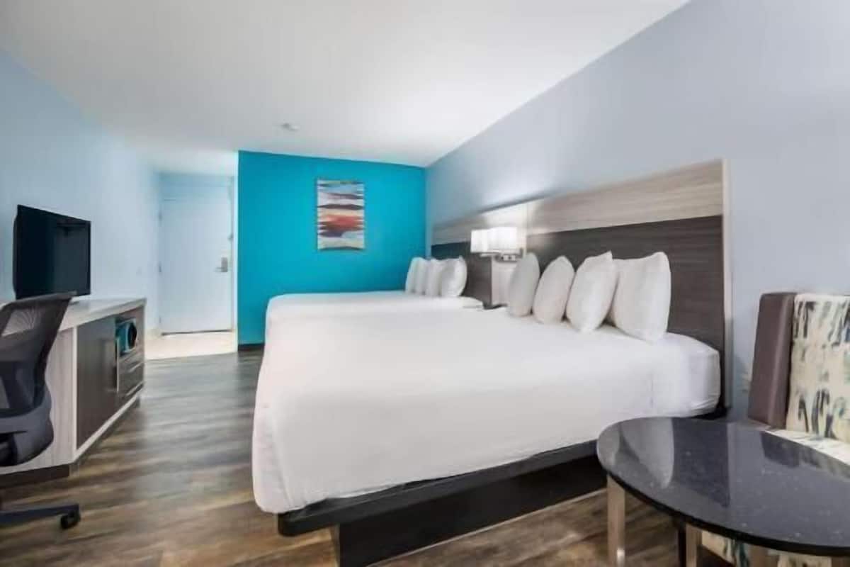 A hotel room with a bed, a desk, a chair, and a TV.