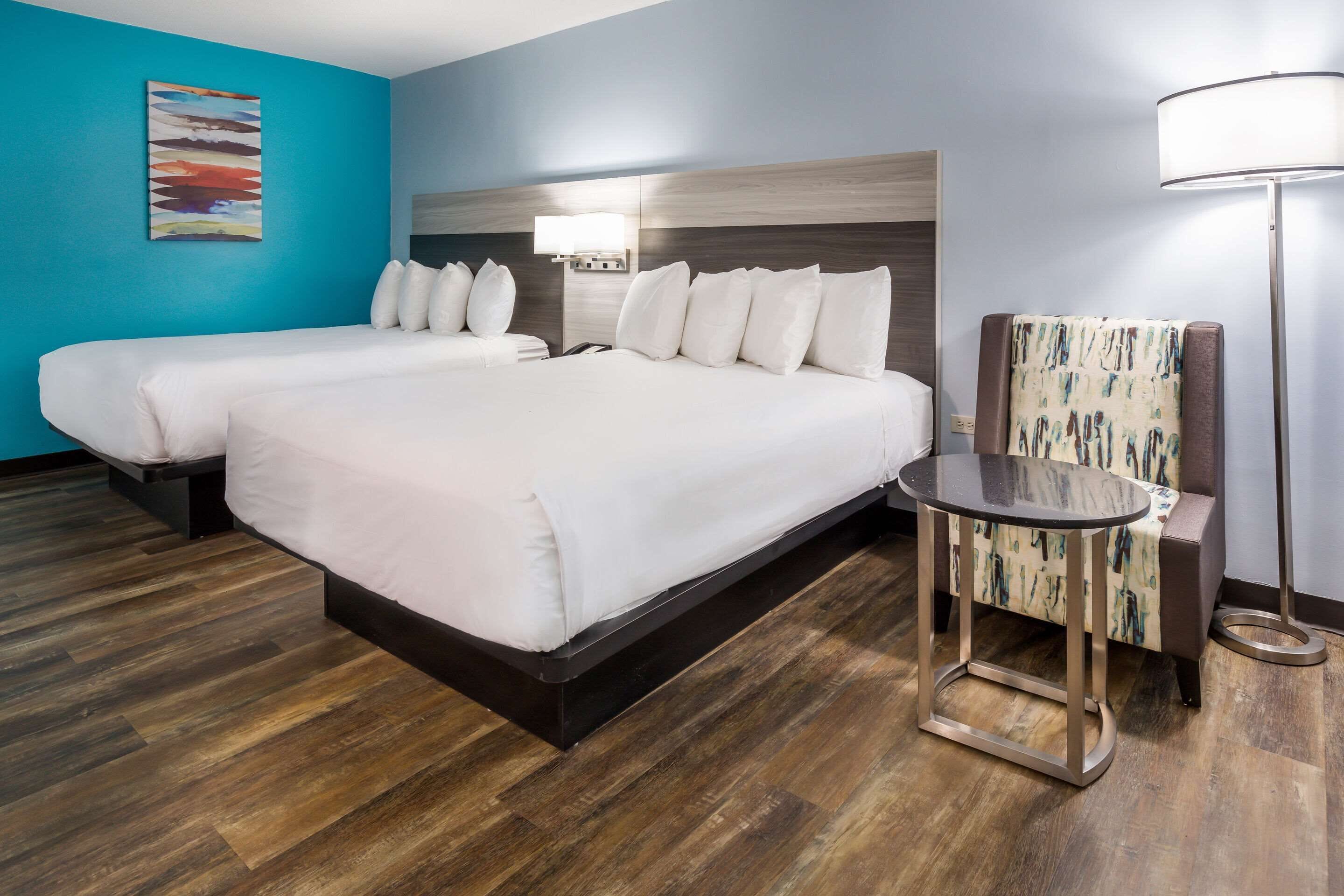 A hotel room with a large bed, a smaller bed, a desk, and a chair.