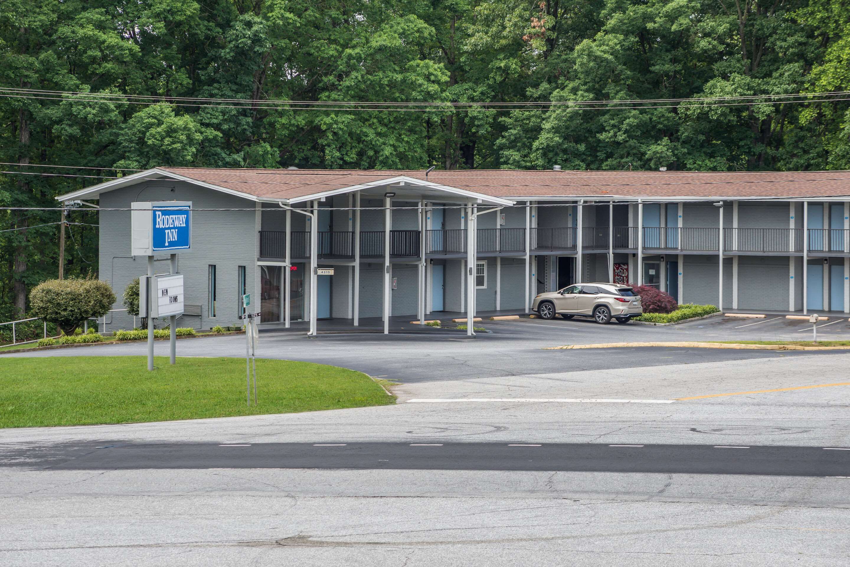 Een motel met een gebouw van twee verdiepingen, een parkeerplaats en een bord met de naam 'Rodeway Inn' erop.