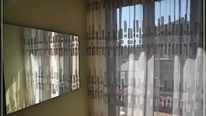 Una habitación con un espejo grande en la pared y cortinas translúcidas con un diseño geométrico.