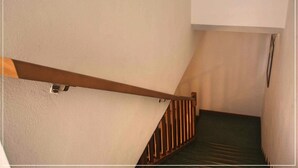 Una escalera con barandilla de madera y un rellano cubierto de alfombra verde.