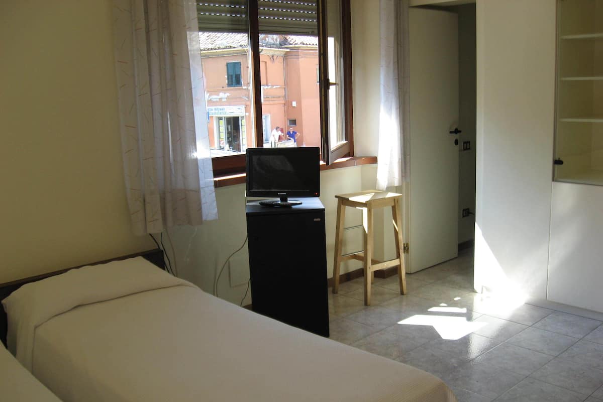 A hotel room with a bed, a desk, a television, and a window with curtains.