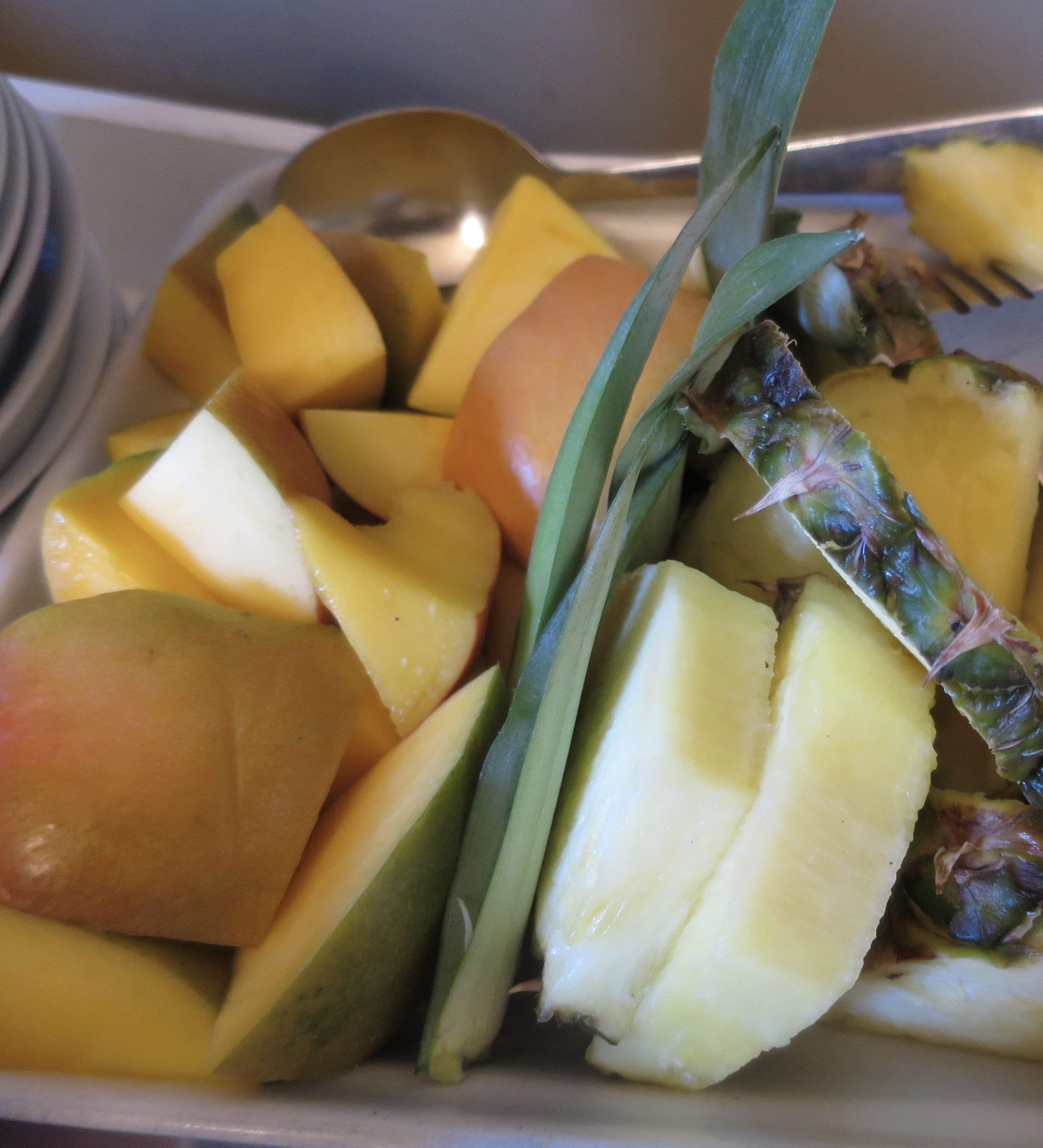 Une assiette de fruits coupés en tranches, notamment de la mangue et de l’ananas.