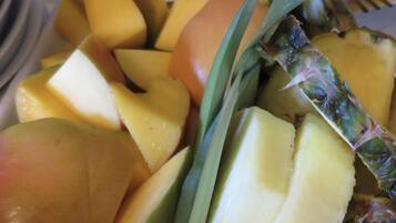 Une assiette de fruits coupés en tranches, notamment de la mangue et de l’ananas.