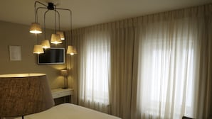 Una habitación de hotel con una cama, un escritorio con lámpara, un televisor y una silla.