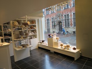 A boutique hotel interior with a display of hats and a view of a historic building outside. - Hotel Alegria (Bruges)