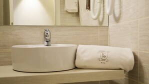 Un baño con un lavabo redondo, una toalla con un logotipo y un espejo sobre el lavabo.
