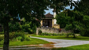 A stone building with a tiled roof, surrounded by lush greenery and a gravel path leading to it. - Domaine de Borie Chambres d'Hôtes (Bretenoux)