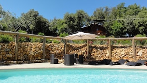 A swimming pool with lounge chairs and an umbrella, surrounded by a stone wall and greenery. - Domaine de Borie Chambres d'Hôtes (Bretenoux)