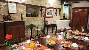 A dining area with a rustic stone wall, wooden furniture, and a variety of breakfast items on the table. - Domaine de Borie Chambres d'Hôtes (Bretenoux)