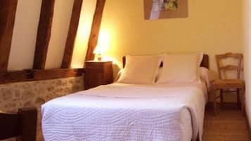 Un dormitorio con cama, mesita de noche, silla y un cuadro en la pared.