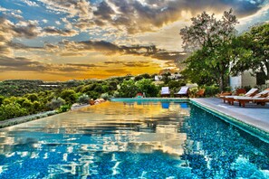 A swimming pool with a view of the sunset, surrounded by greenery and lounge chairs. - Villa Stefanija (Barban)