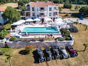 A large, multi-story building with a swimming pool, outdoor seating, and a collection of vintage cars. - Villa Stefanija (Barban)