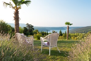 Two wicker chairs with cushions in a grassy field with a view of a lake and mountains. - Villa Stefanija (Barban)