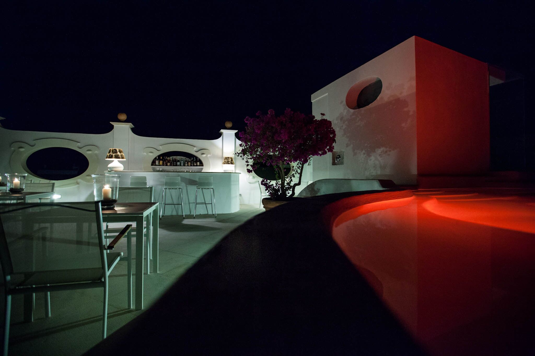A modern outdoor dining area with a bar, seating, and a decorative plant.