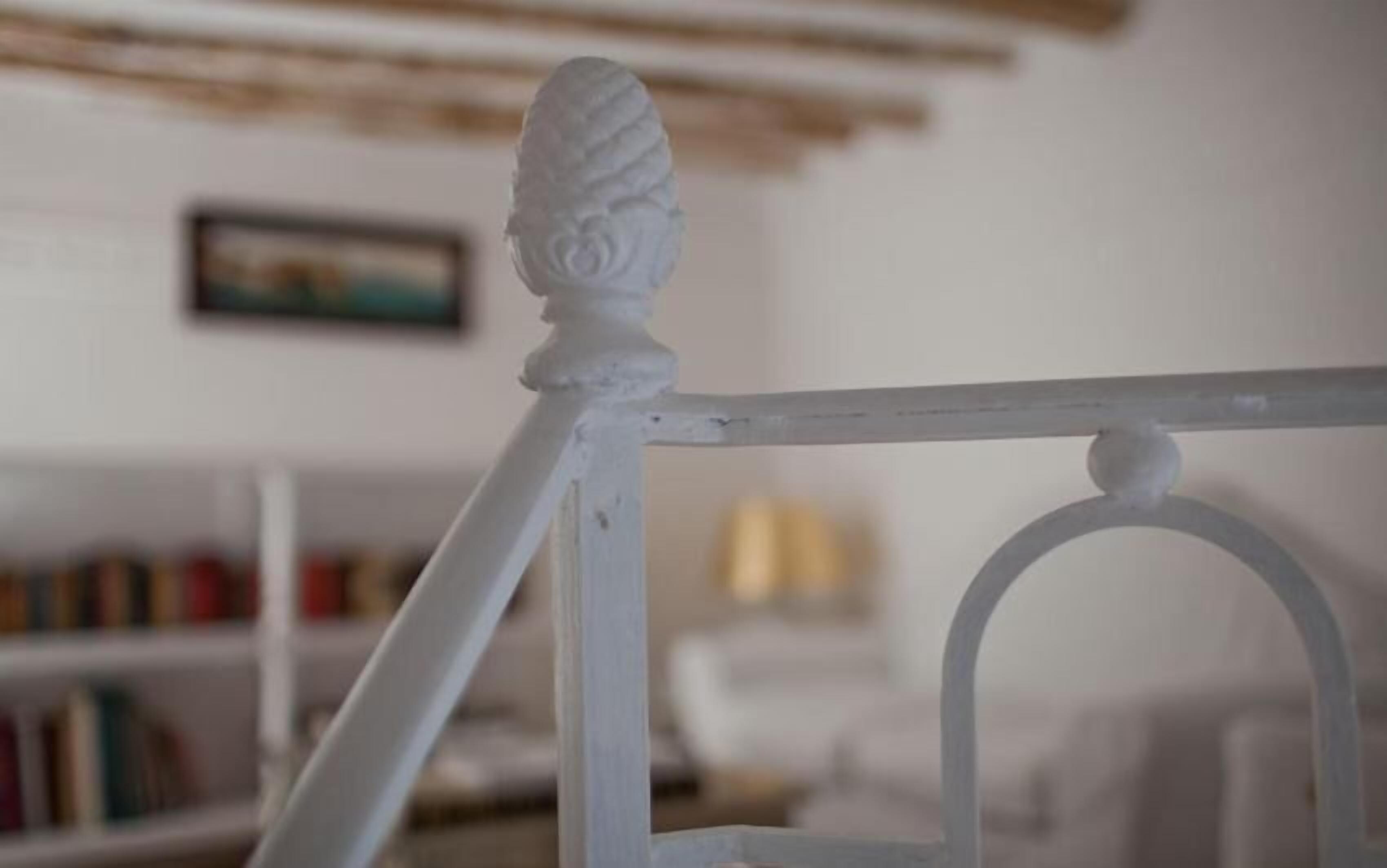 A white metal chair with a decorative finial.
