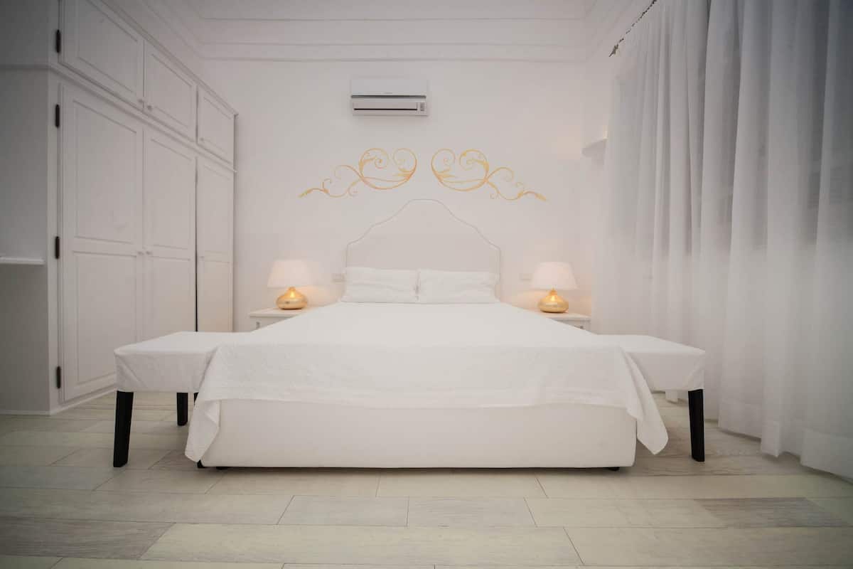 Une chambre moderne avec un grand lit, des murs blancs et un climatiseur au plafond.