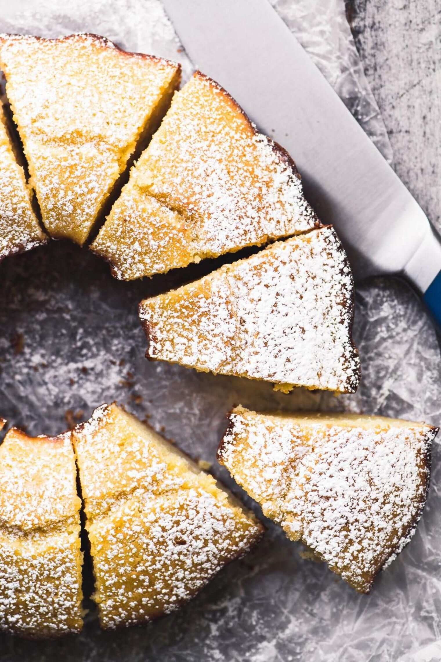 Ein Kuchen mit Puderzucker, auf einer Fläche platziert.
