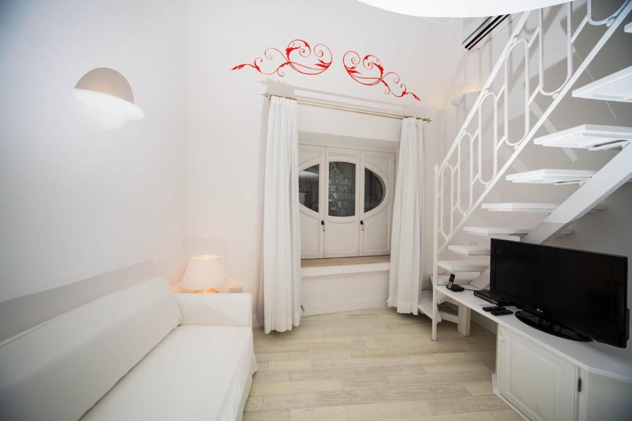 Une chambre à coucher moderne avec un lit blanc, un téléviseur et un escalier.