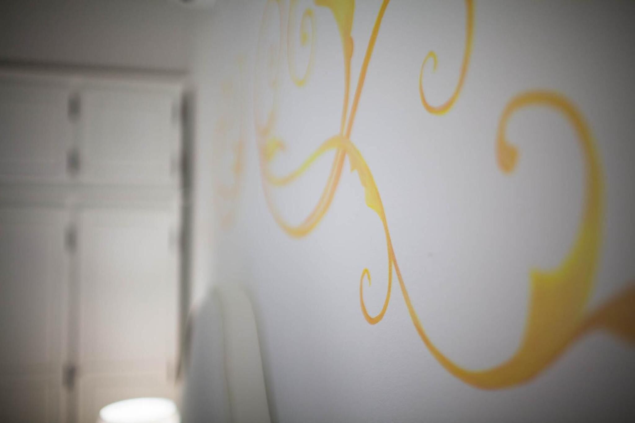 A bathroom with a white wall and a yellow decorative design.