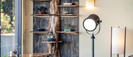 A room with a central wooden tree trunk supporting shelves, a desk, and chairs.