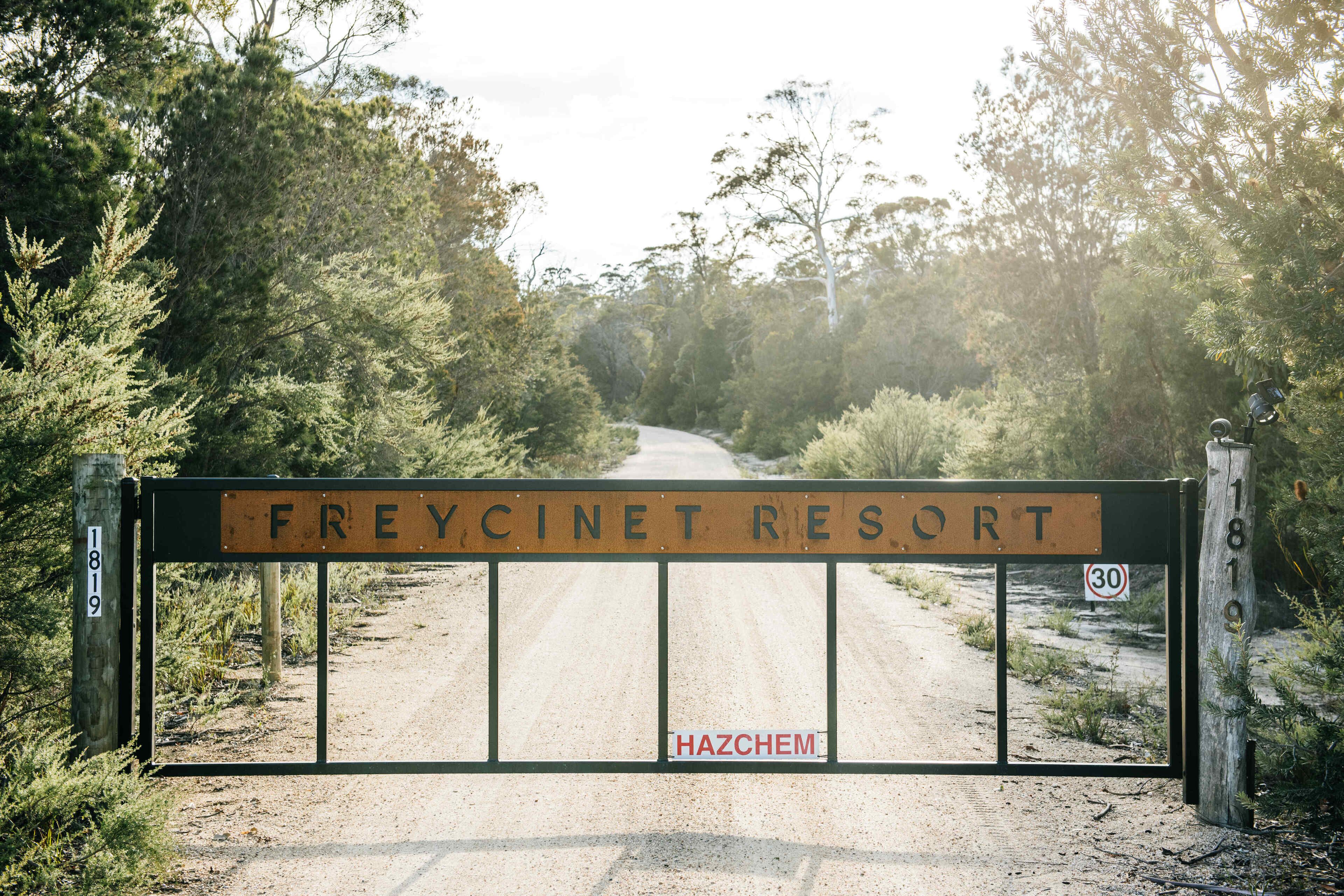 Een hekpoort naar Freycinet Resort, met een onverharde weg door dichtbegroeid terrein.