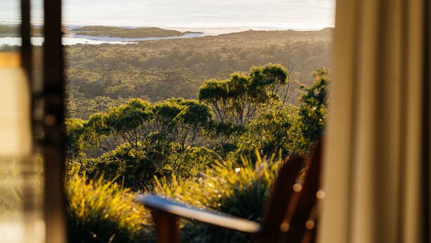 A view from a room with a large window overlooking a coastal landscape.