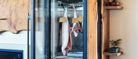 Una cocina moderna con refrigerador empotrado, estanterías de madera y una obra de arte original en la pared.