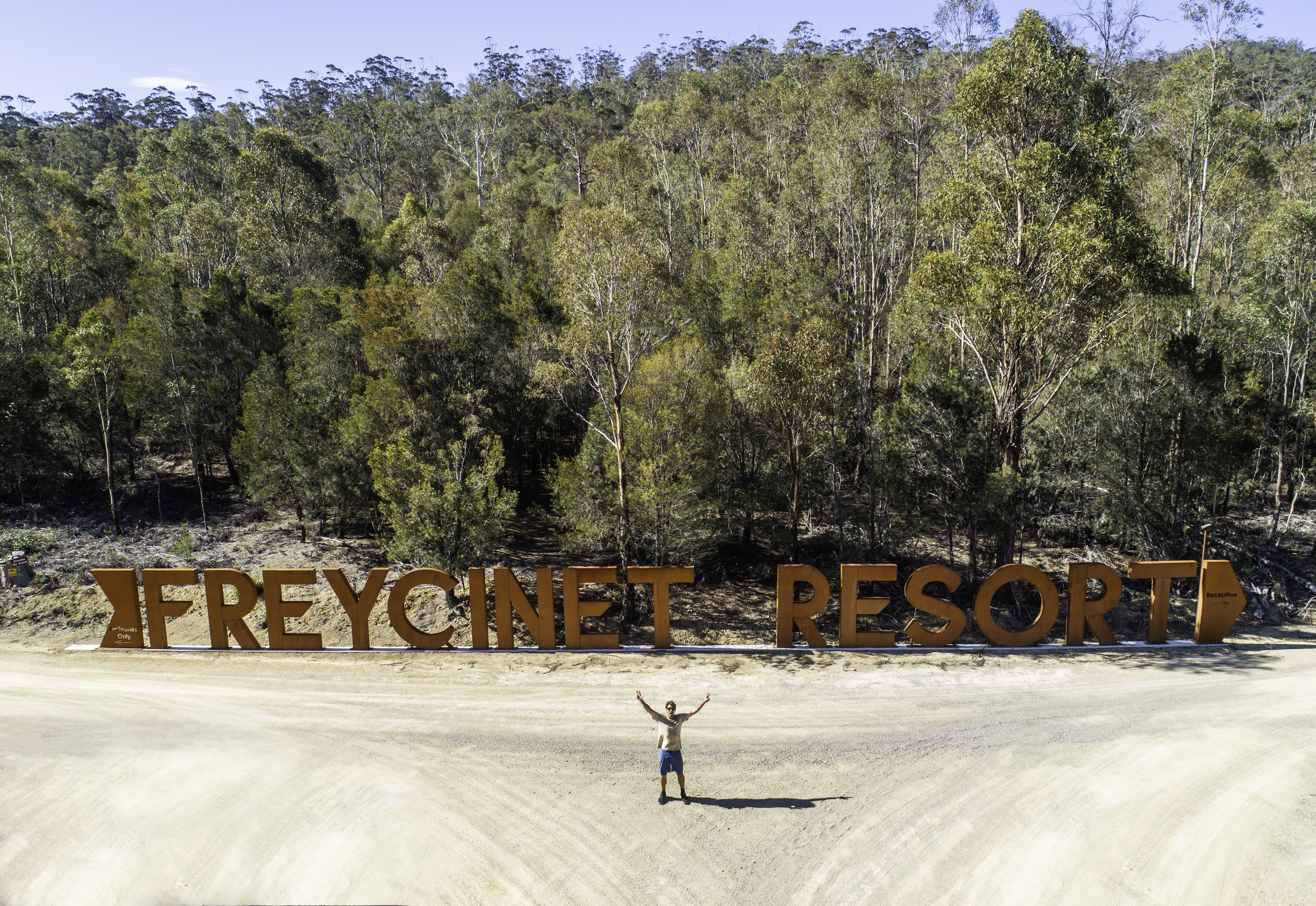 A person standing in front of large letters spelling "FREYCINET RESORT".