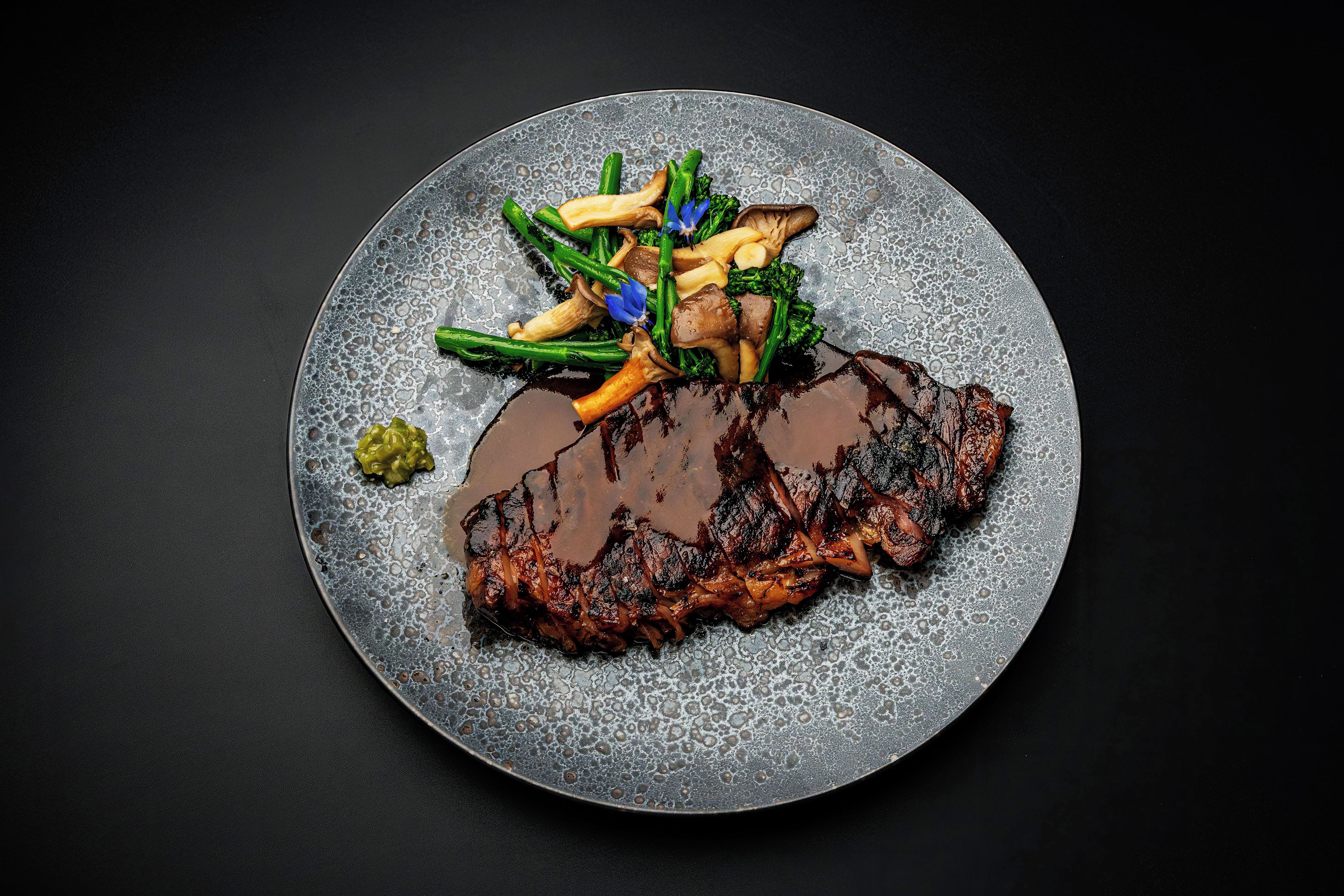 Un plato con un bistec, judías verdes y papas fritas.