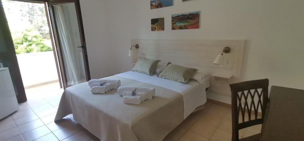 A bedroom with a bed, bedside lamps, a table, and a chair.