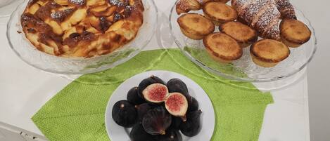 A table with three glass dishes containing baked goods and a plate of figs on a green placemat.