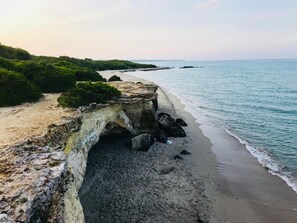Paisaje costero con un acantilado rocoso y una playa.