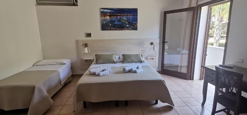 A hotel room with a bed, a smaller bed, a desk, and a chair.