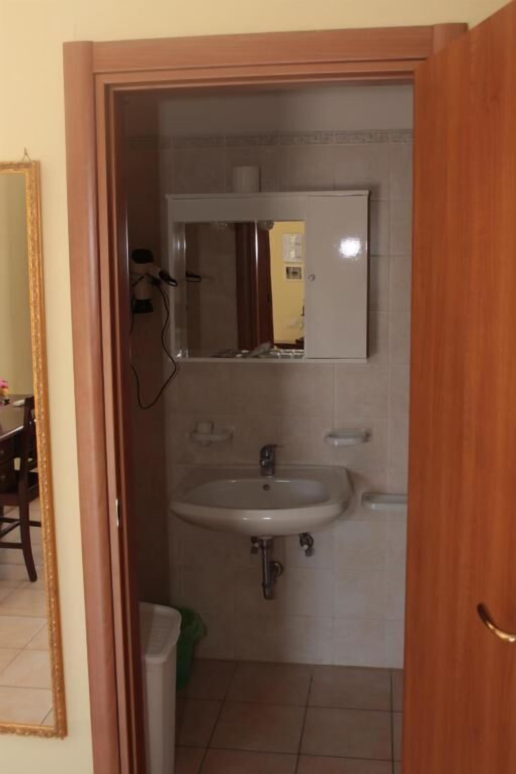 Un baño con lavamanos, espejo e inodoro.