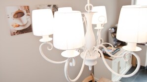 Un comedor con candelabro, una mesa dispuesta para dos personas y un frutero con fruta.