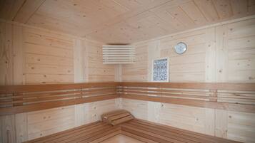 Eine Sauna mit Holzwänden und -bänken, einer Uhr und einem Poster mit Symbolen.