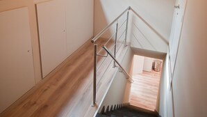 Una escalera con piso de madera, barandillas de metal y tragaluz.