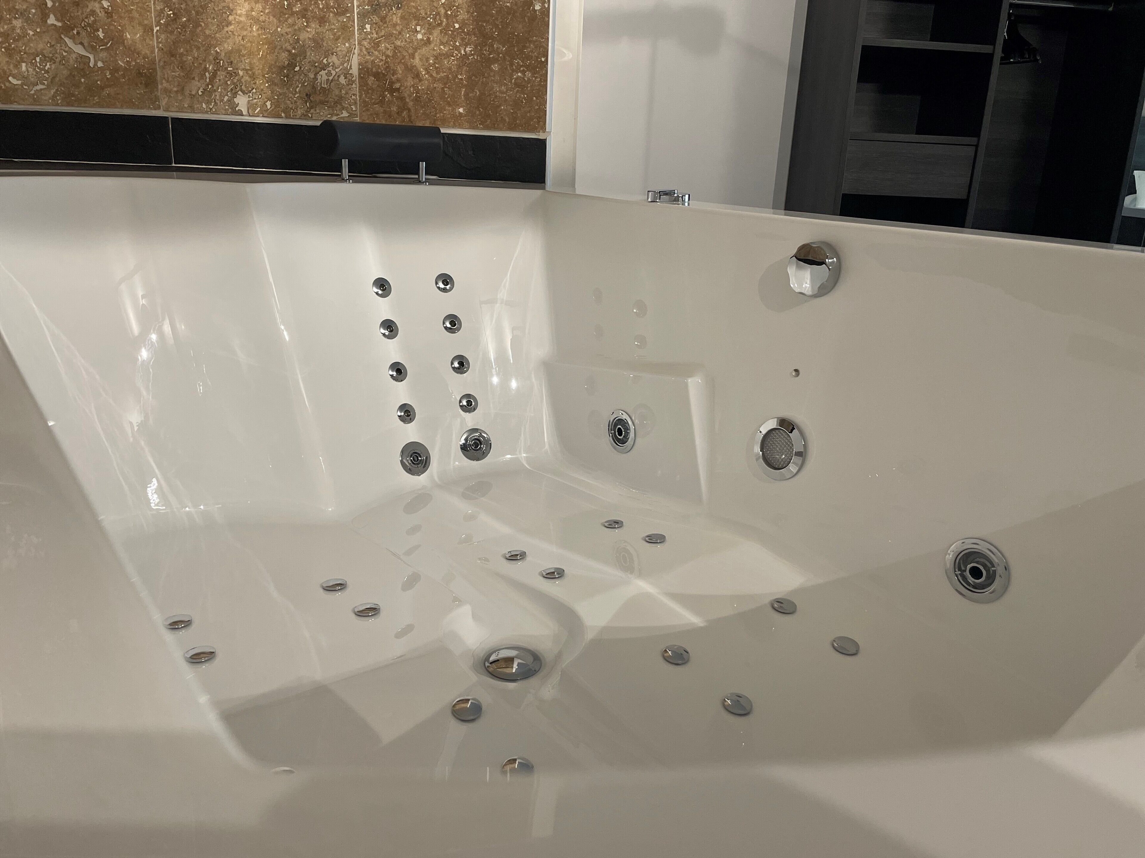 A white bathtub with multiple faucets and drainage holes.