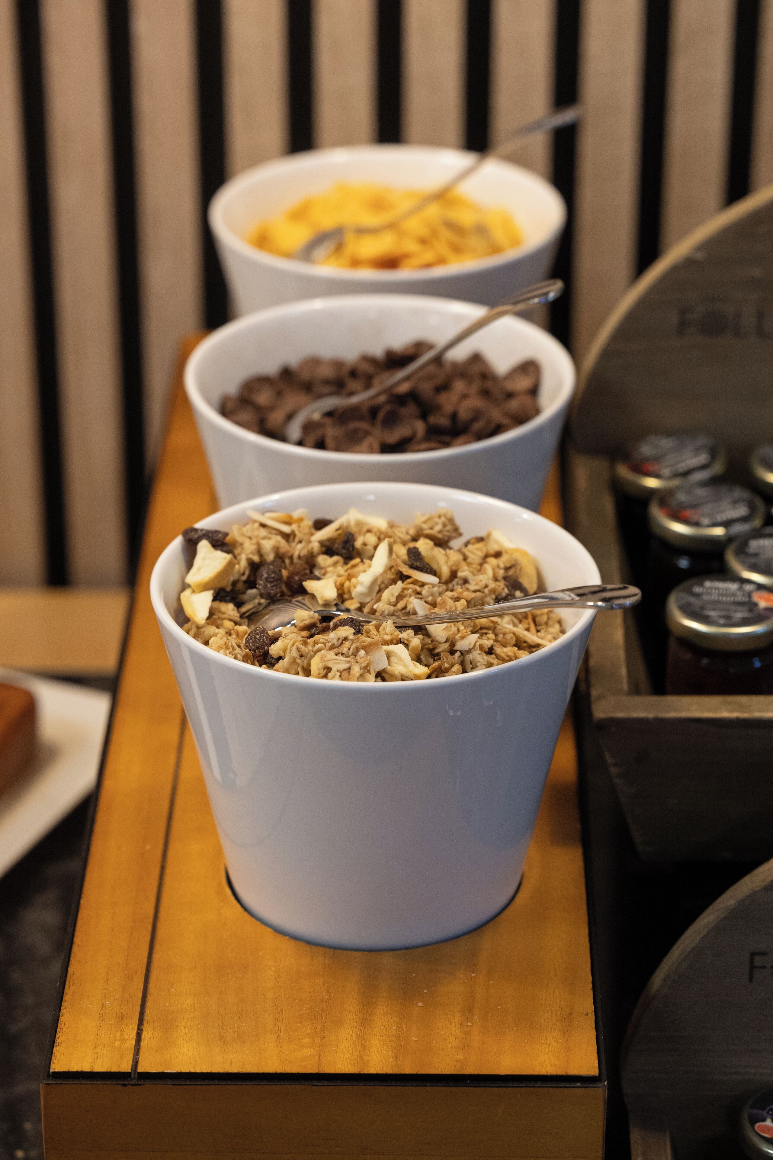 Three bowls of cereal on a wooden table.