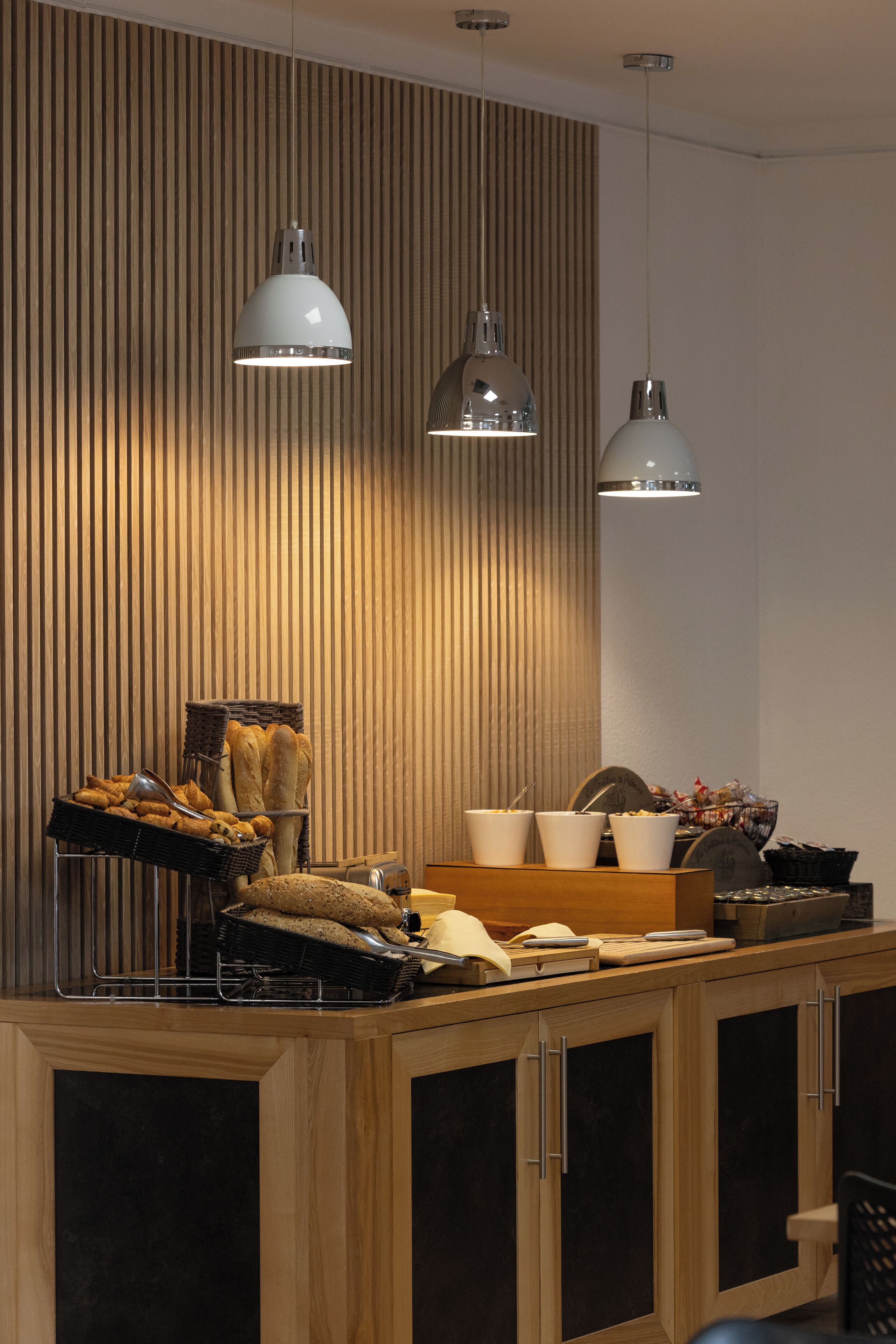 A modern kitchen with wooden cabinets, a central island with a sink, and hanging pendant lights.