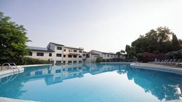 A swimming pool with clear blue water, surrounded by buildings and trees.