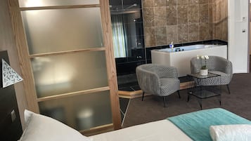 Hotellihuoneessa on sänky, kaksi tuolia, pieni pöytä, pesuallas ja suihkutila.